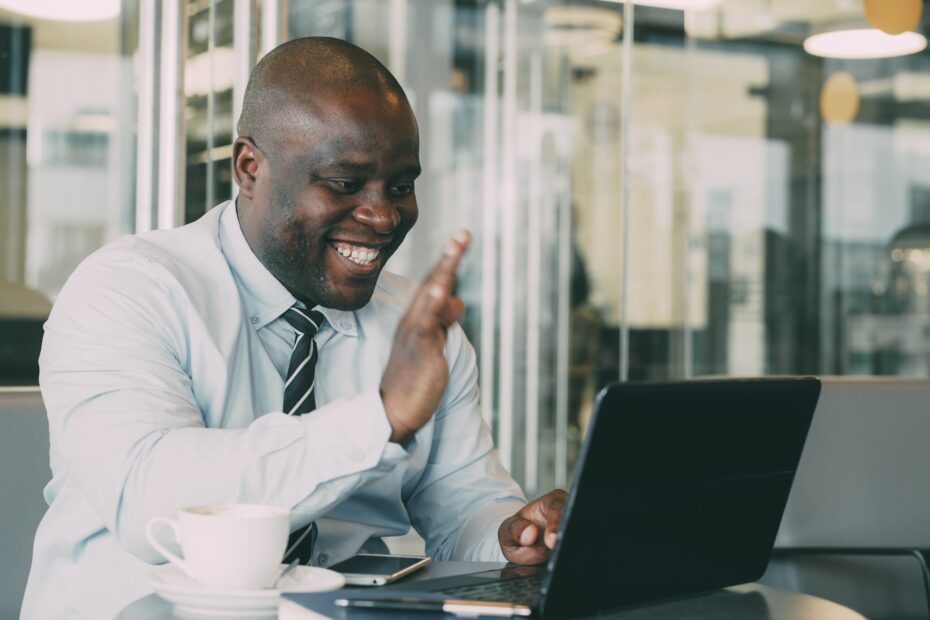 Man waving during a video call on laptop.